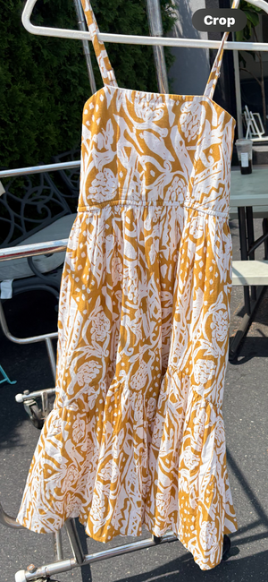 Printed strappy midi dress with side pockets on a hanger blowing in the breeze.