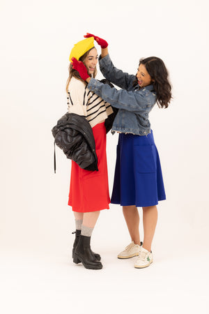 Two friends celebrating the season in Mirelle two pocket midi skirts in rouge/red and electric blue.