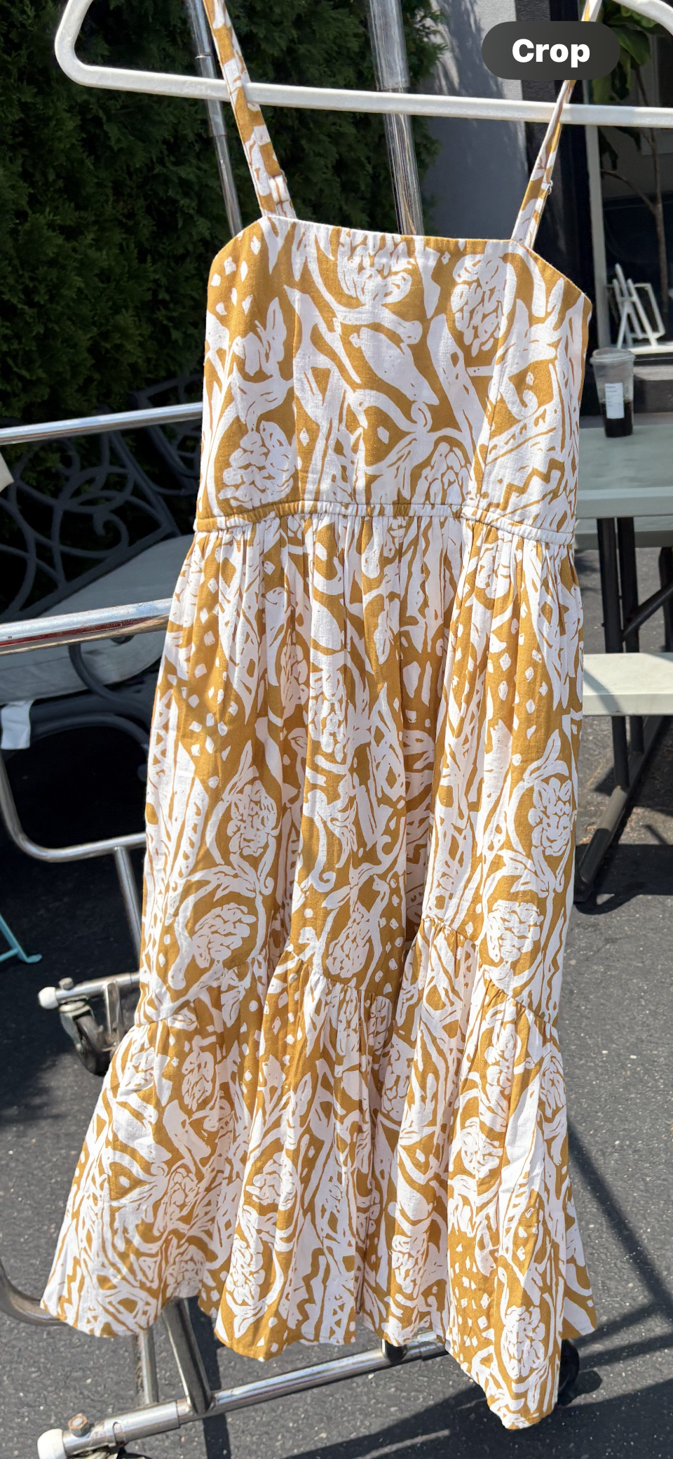Printed strappy midi dress with side pockets on a hanger blowing in the breeze.