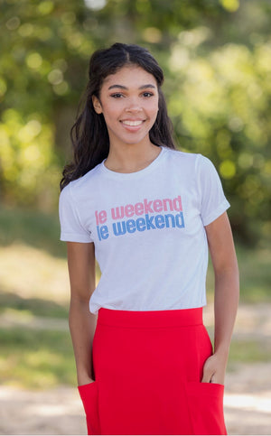 Casually chic French woman in red Mireille skirt and French graphic tee that says,  "le weekend " standing in Paris's Jardin du Luxembourg