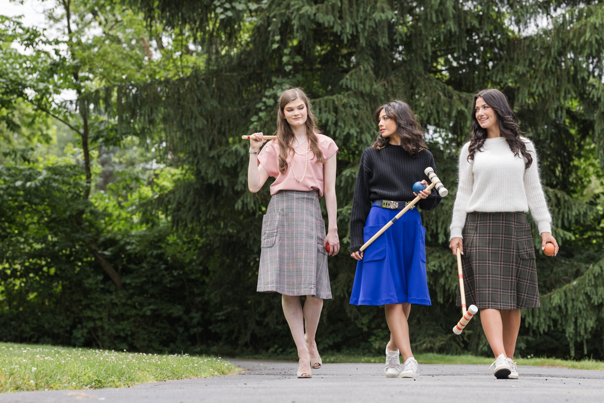 3 young women ready to play croquet all wearing the Mireille midi skirt in different patterns and colours.