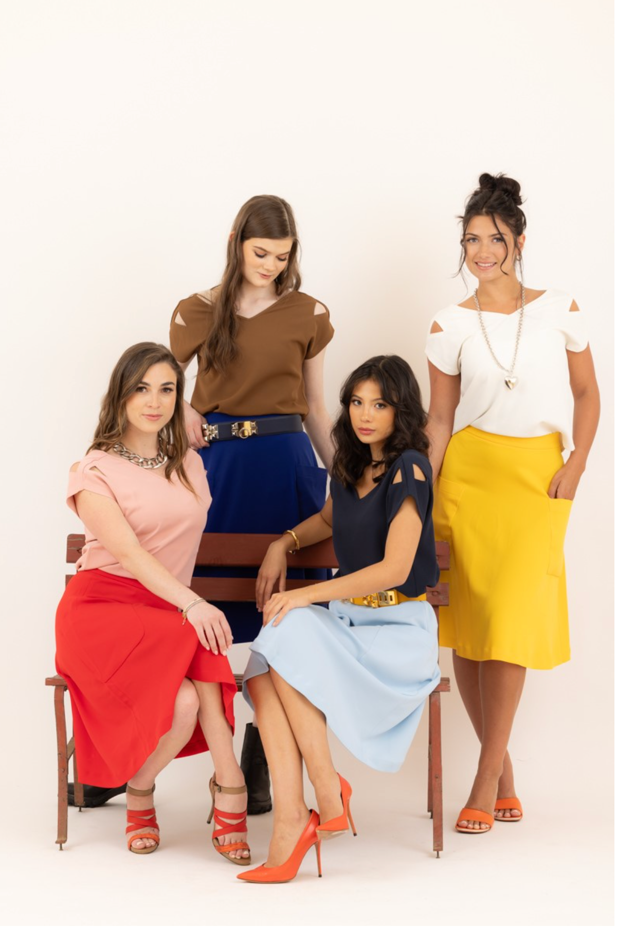 Four women modeling Le Mireille Marche outfits, featuring colorful midi skirts and Julie tops in pink, brown, navy, and white.