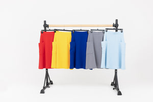 Ballet barre displaying colorful midi skirts from Le Mireille Marche in red, yellow, electric blue, gray, and baby blue.