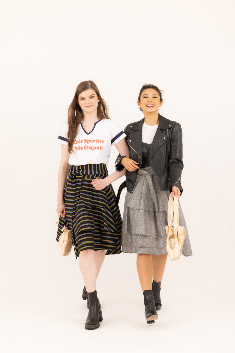 Two ballerinas "off duty" both wearing the Valerie wrap skirt from Le Mireille Marche.  One ballerina is wearing the "très sportive, très élégante graphic tee and the other ballerina is wearing a leather bustier and a leather motorcycle jacket.