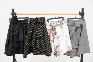 A ballet barre displaying all of the colour ways of the Valerie wrap skirt, including the grey and white pinstripe, the multi colour stripe, the cherry blossom print and the black and white stripe.